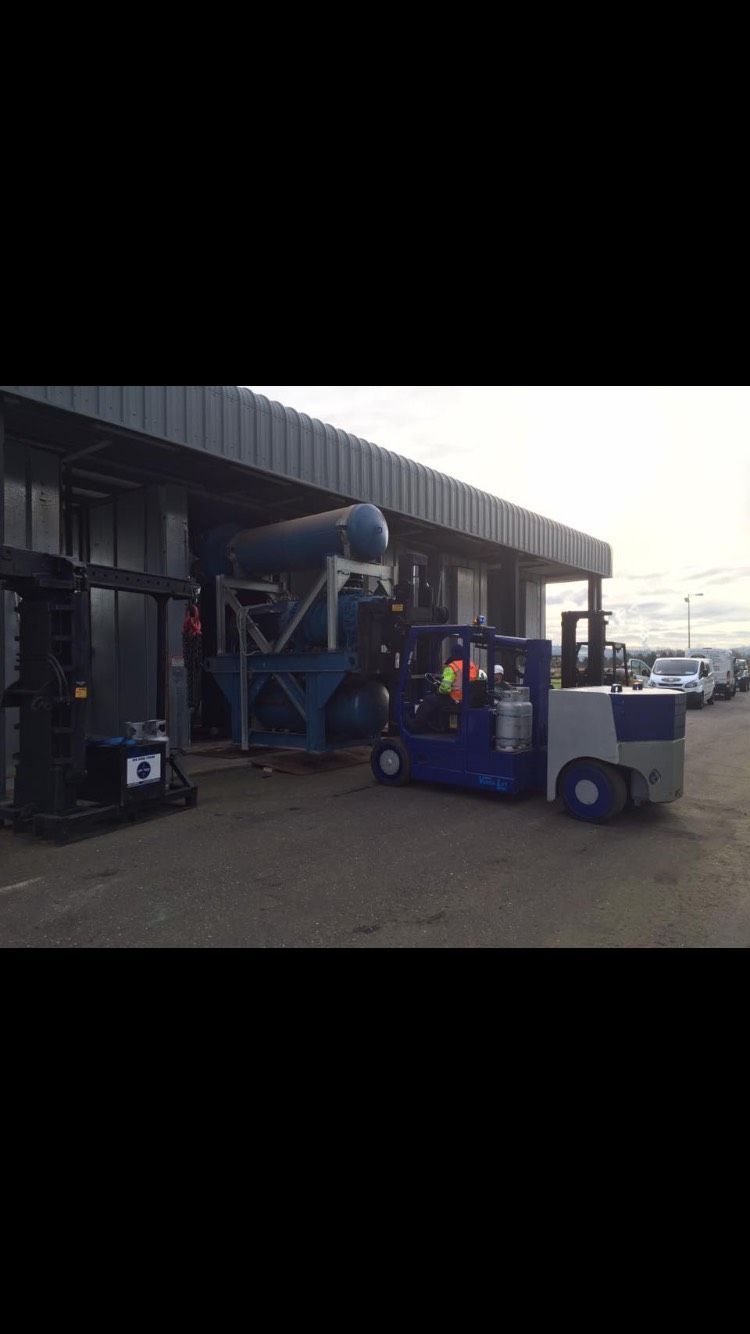 Blue forklift loading equipment into a factory