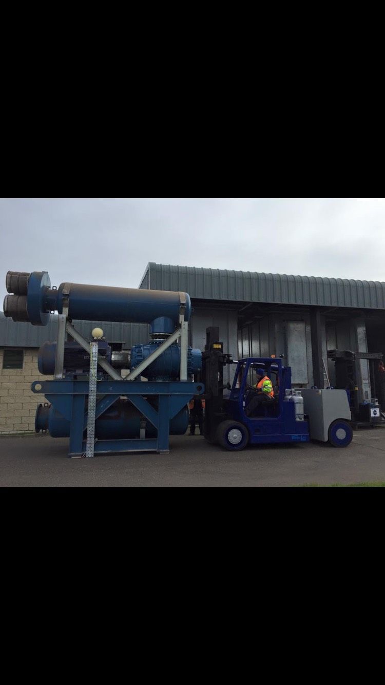 Blue forklift moving large industrial equipment