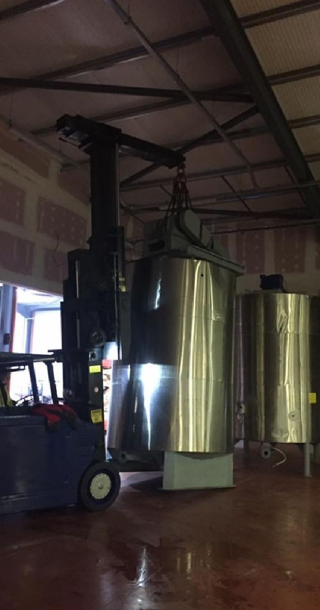 Blue forklift moving industrial brewing equipment