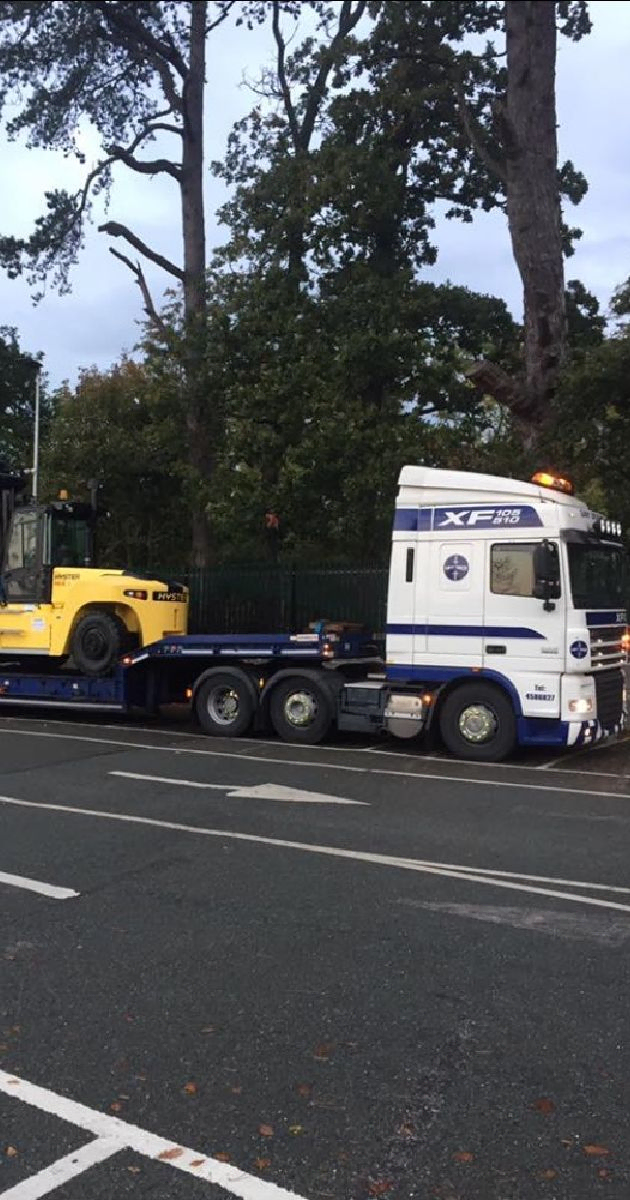 Yellow forklift being transfered on a Lorry